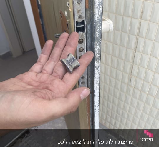 יד מחזיקה חלק מתכת ליד מנעול דלת פתוחה